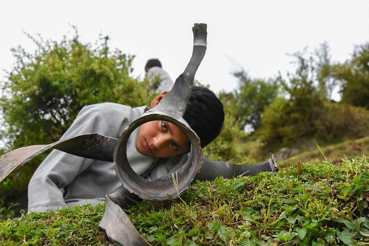  A boy looks through the tail of an artillery shell after unprovoked firing by the Pakistani forces at LoC (PTI Photo)