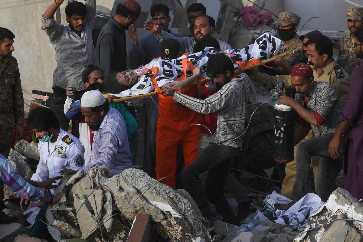 Pakistani volunteers move out an injured woman from the rubble of a collapsed five-storey residential building in Karachi on March 5, 2020. (Photo by AFP)