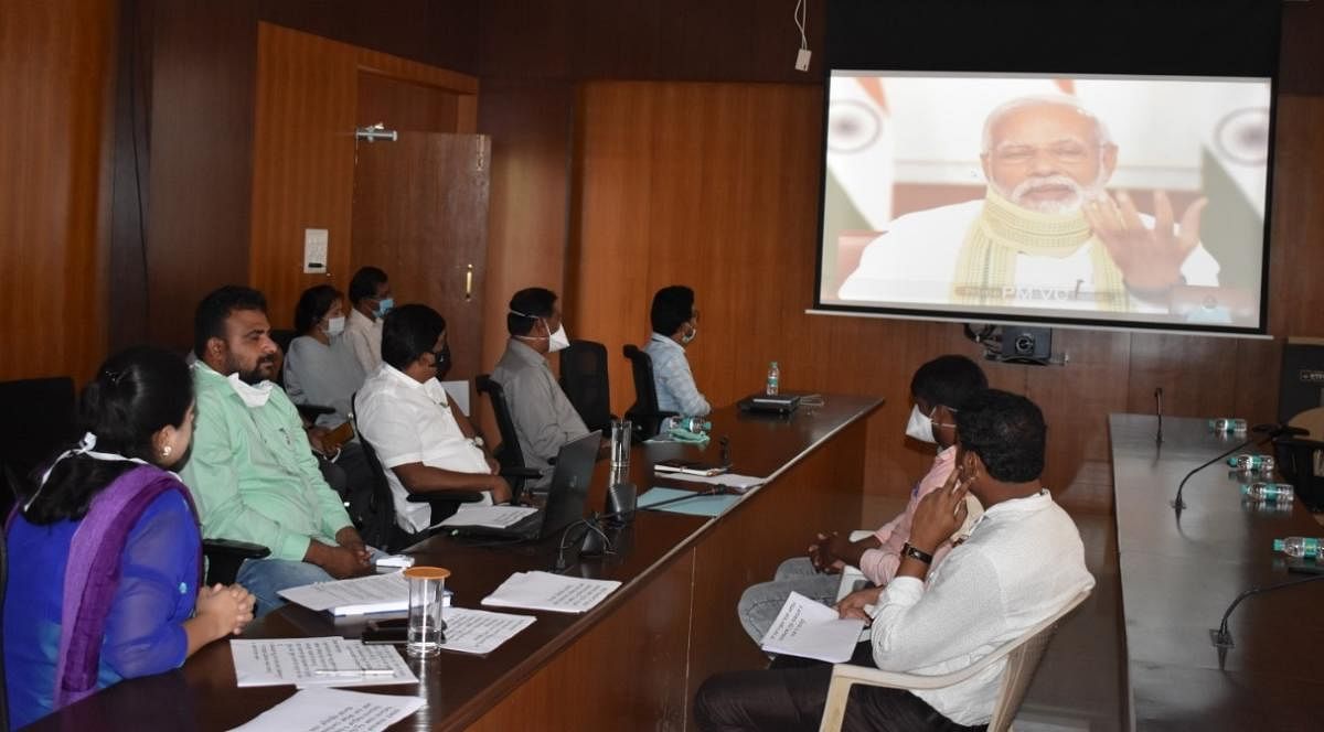 Prime Minister Narendra Modi interacts with Watadahosahalli Gram Panchayat president S M Naveen via video conferencing at mini auditorium of Zilla Panchayat on Friday.