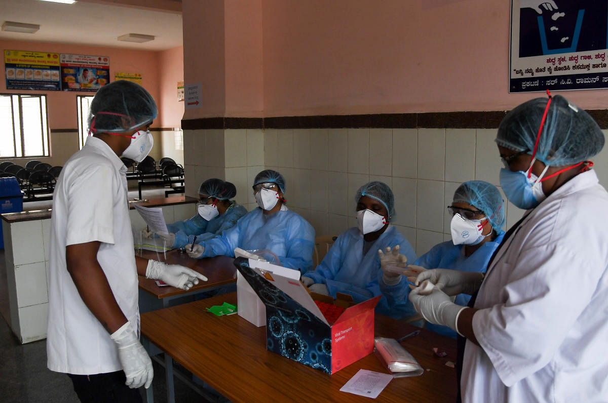 A Health department employee collects a thorat swab sample at the test center at C V Raman Nagar Hospital, in Bengaluru on Friday. Photo/ B H Shivakumar