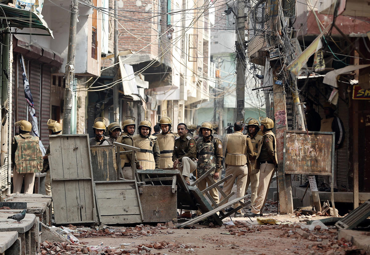 Police officers stand guard in an alley in a riot affected area following clashes between people demonstrating for and against a new citizenship law in New Delhi. Credit: Reuters Photo