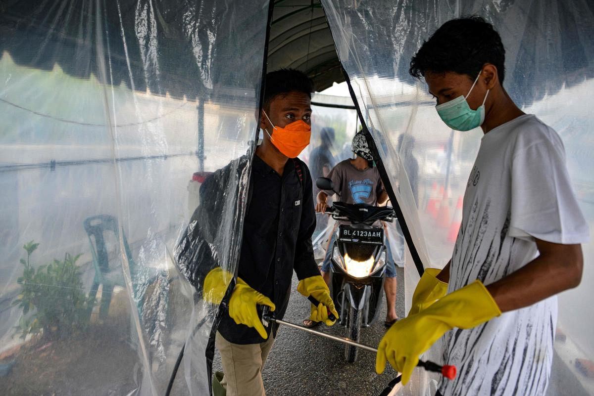 A volunteer talks with a colleague at a disinfectant chamber (AFP Photo)