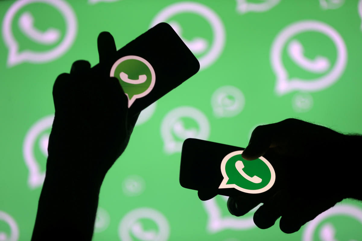 Men pose with smartphones in front of the displayed Whatsapp logo in this illustration. Photo by REUTERS