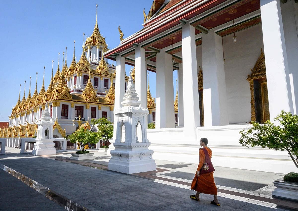 A Buddhist monk walks towards Loha Prasat at Wat Ratchanatdaram temple in Bangkok. (Photo by AFP)