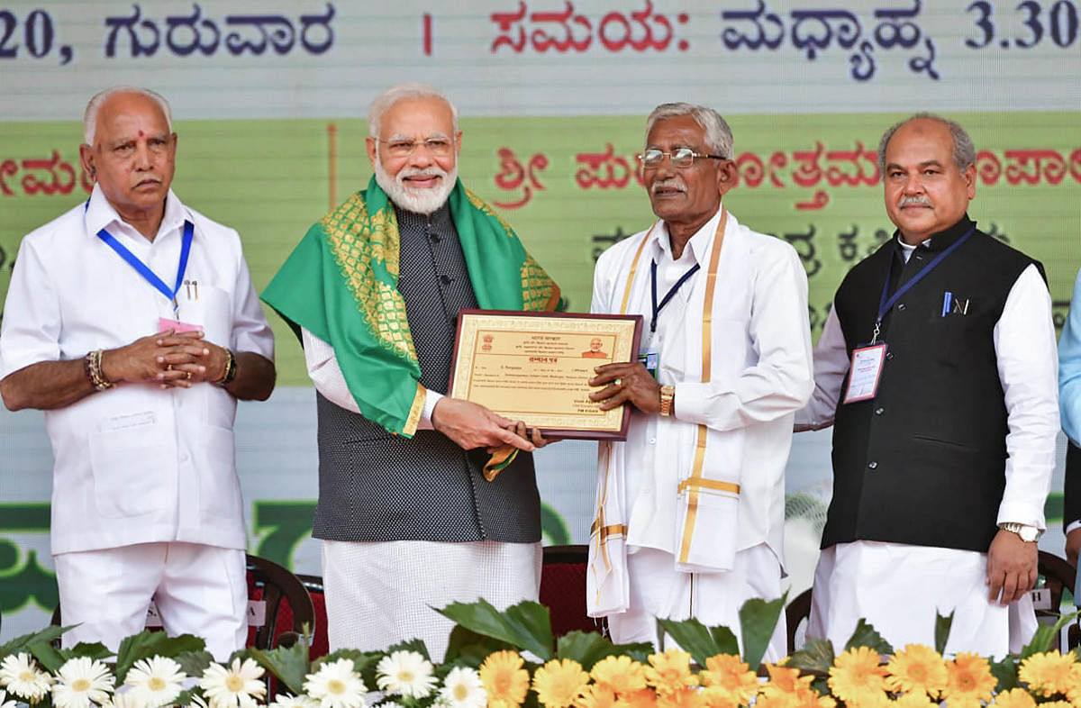 Tumakuru: Prime Minister Narendra Modi presents an award to a farmer after he approved a proposal to extend the benefit of Rs 6,000 per year under the PM-KISAN scheme to all farmers in the country, during his address to a gathering, at Tumakuru district, Thursday, Jan. 2, 2020. Karnataka Chief Minister B S Yediyurappa is also seen. (PTI Photo)