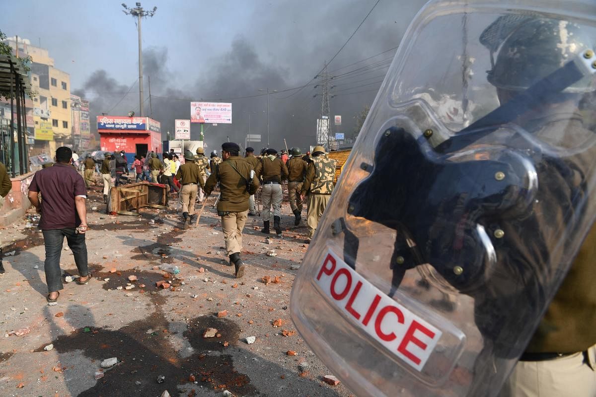Delhi: Riot police walk along a road scattered with stones following clashes between supporters and opponents of a new citizenship law, at Bhajanpura area of New Delhi. (AFP Photo)