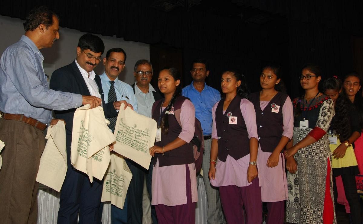 Deputy Commissioner M V Venkatesh distributes cloth bags to students at a programme in Mandya on Wednesday. dh photo