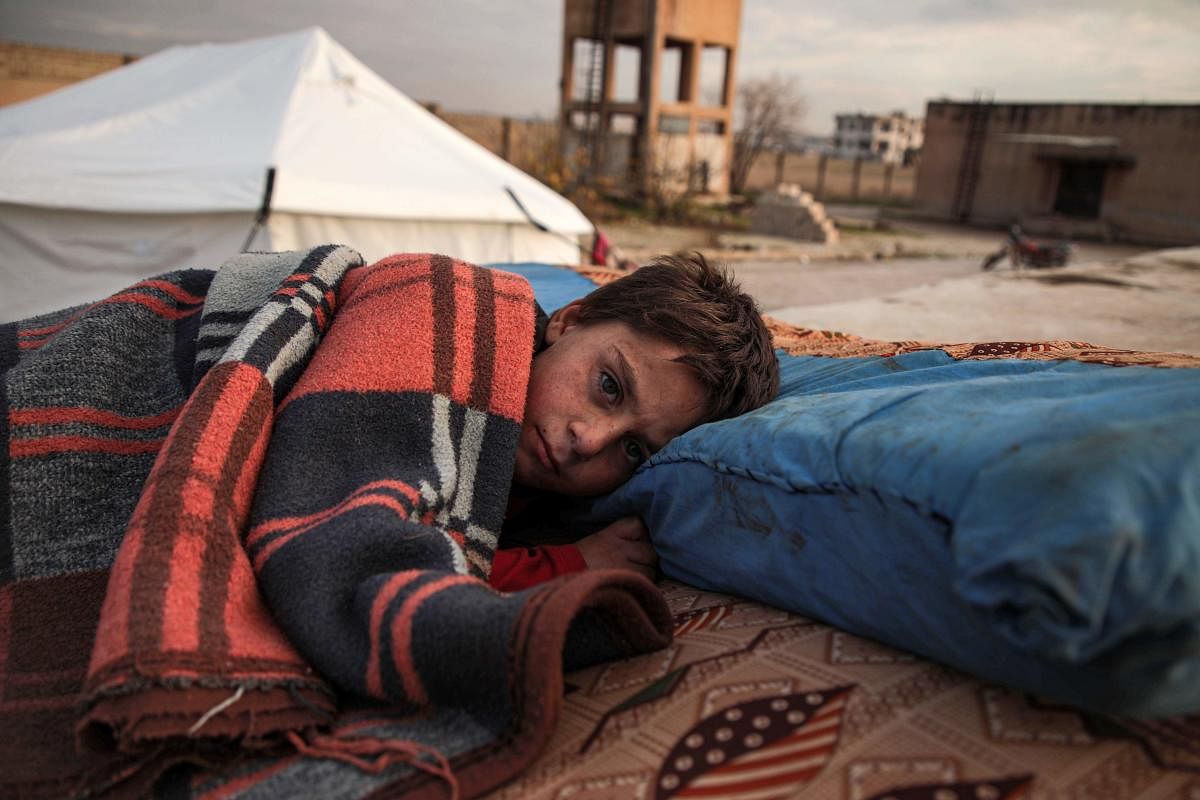 A Syrian child, one of those who fled from government forces' advance on Maaret al-Numan in the south of Idlib prvoince, sleeps on a futon in the open at a camp for the displaced near the town of Dana in the province's north near the border with Turkey, on December 27, 2019. (Photo by Aaref WATAD / AFP)