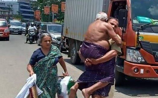 Kerala man carries father as police blocks vehicle (DH Photo/Arjun Raghunath)