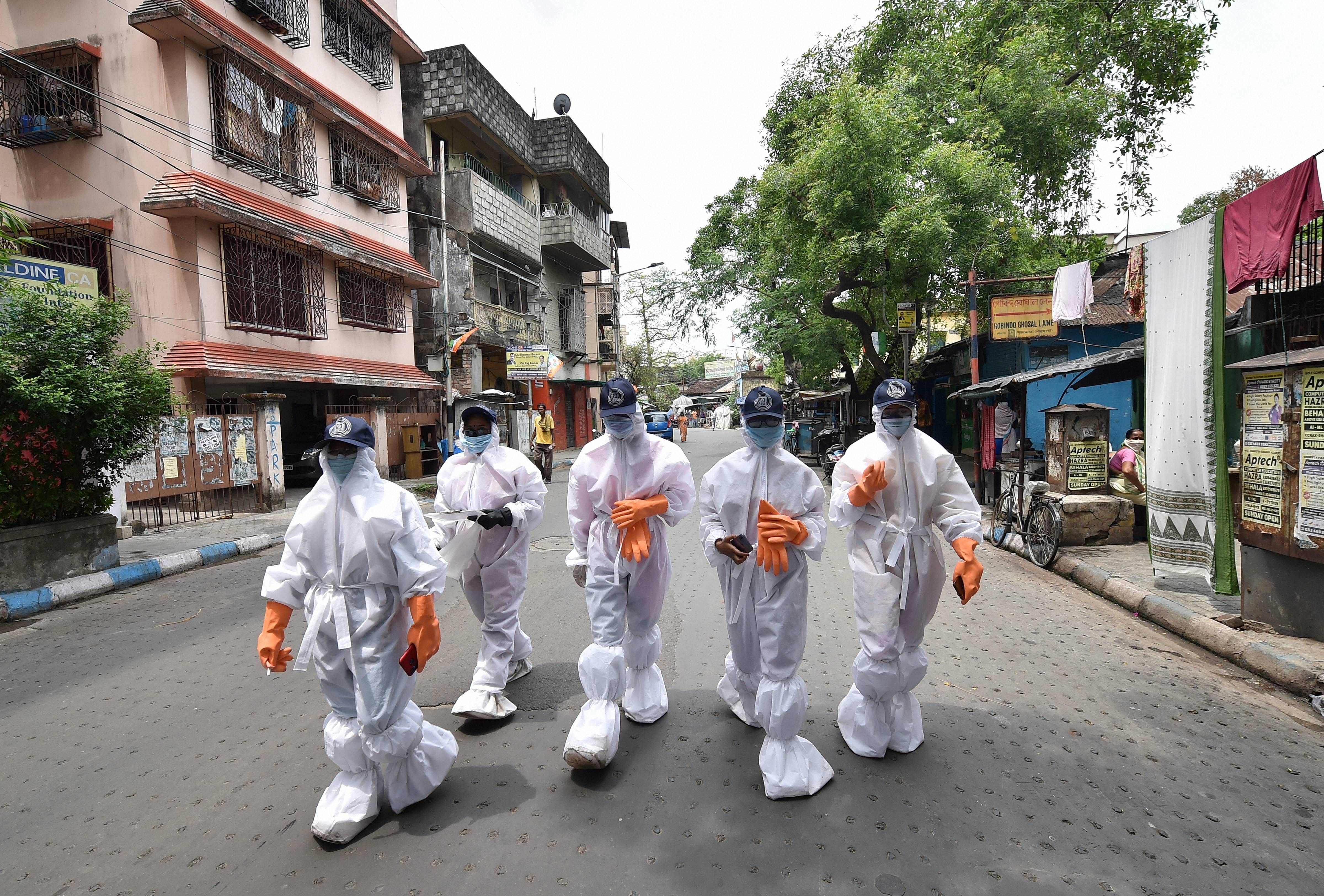 Health workers wearing protective suits walk in a locality during their door-to-door surveillance to detect COVID-19 cases. (PTI Photo)