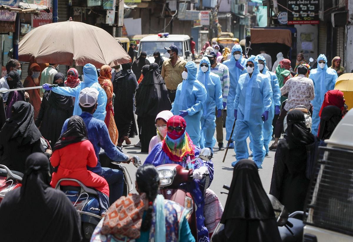 Police personnel wearing protective suit urge people to maintain social distance following relaxation of restrictions for few hours, during the nationwide lockdown to curb the spread of coronavirus, in Ahmedabad, Wednesday, April 22, 2020. (PTI Photo)
