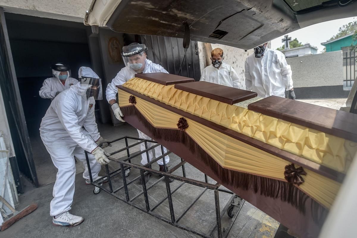 Mortuary workers move the coffin of a COVID-19 victim at a crematorium (AFP Photo)