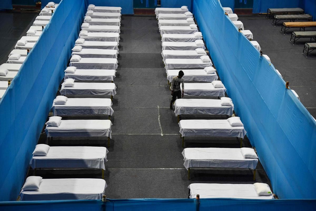 A worker arranges beds in a quarantine centre in an indoor stadium in Guwahati on Sunday. AFP