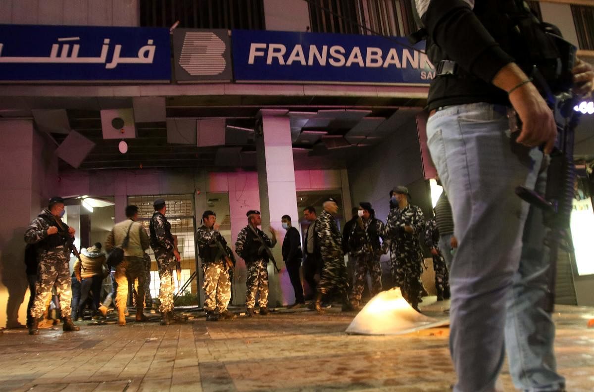 Lebanese security forces inspect the entrance of a Fransabank branch in Lebanon's southern city of Sidon on April 25, 2020, after unknown assailants targeted the bank entrance with an explosive device. (Photo by AFP)