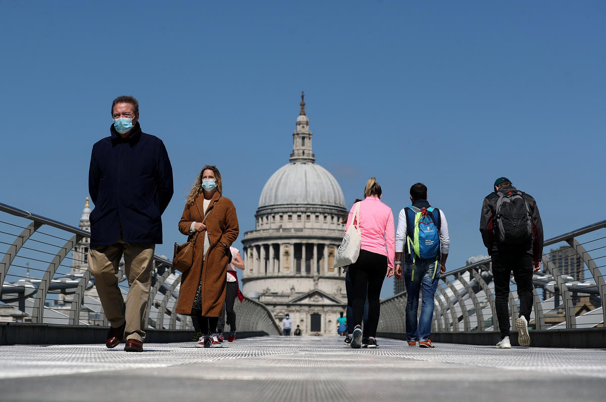 People wearing face masks cross Millennium Bridge, as the spread of the coronavirus disease (Reuters Photo)