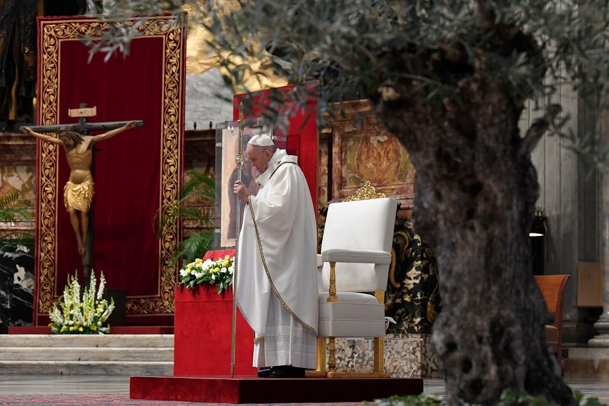 This photo taken and handout on April 12, 2020 by the Vatican Media shows Pope Francis gather his thougths, by a miraculous crucifix (Rear L) that in 1552 was carried in a procession around Rome to stop the great plague, during Easter Sunday Mass on April 12, 2020. Credit: AFP Photo