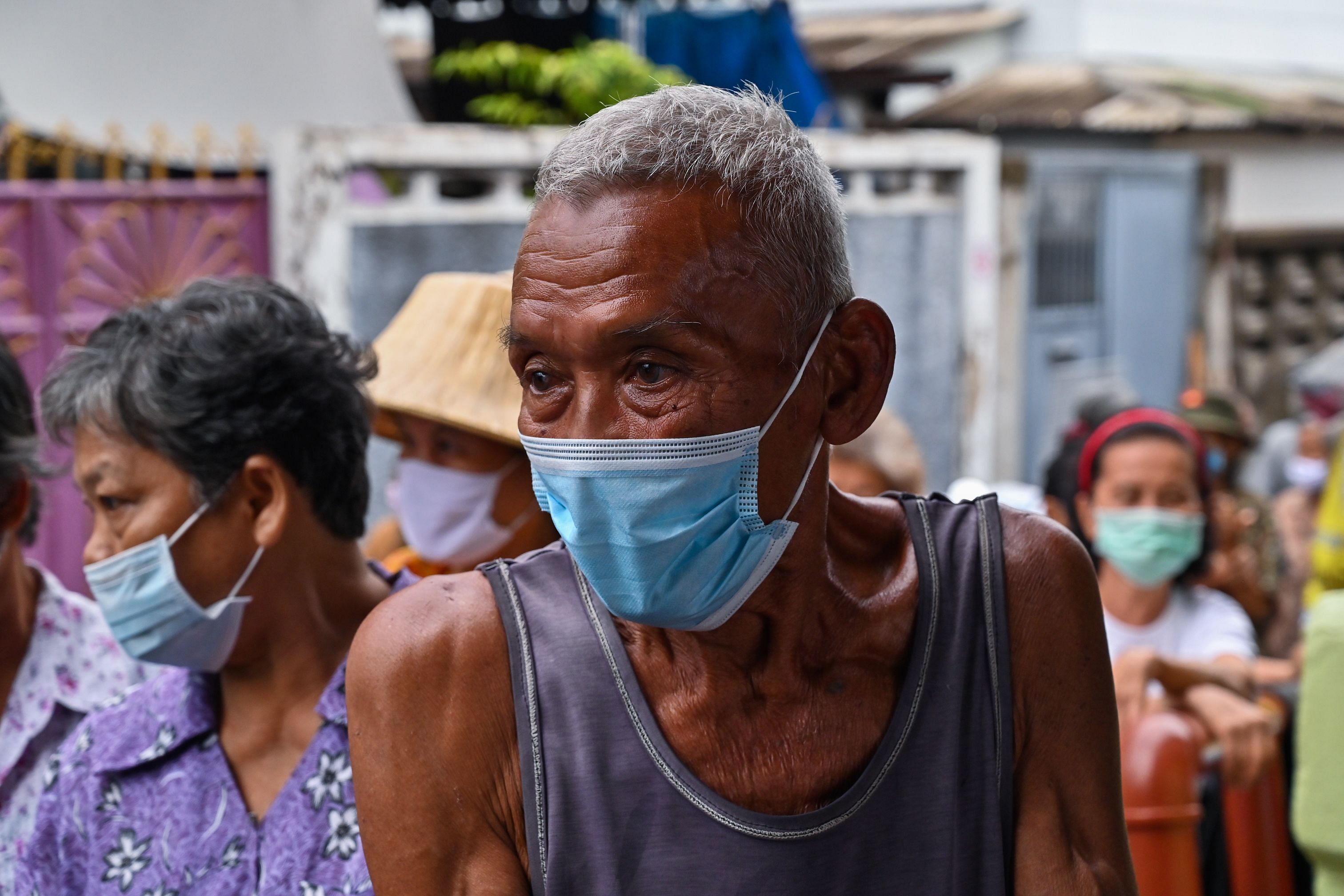 Elderly people line up for food and cash donations in a Bangkok district. (AFP)