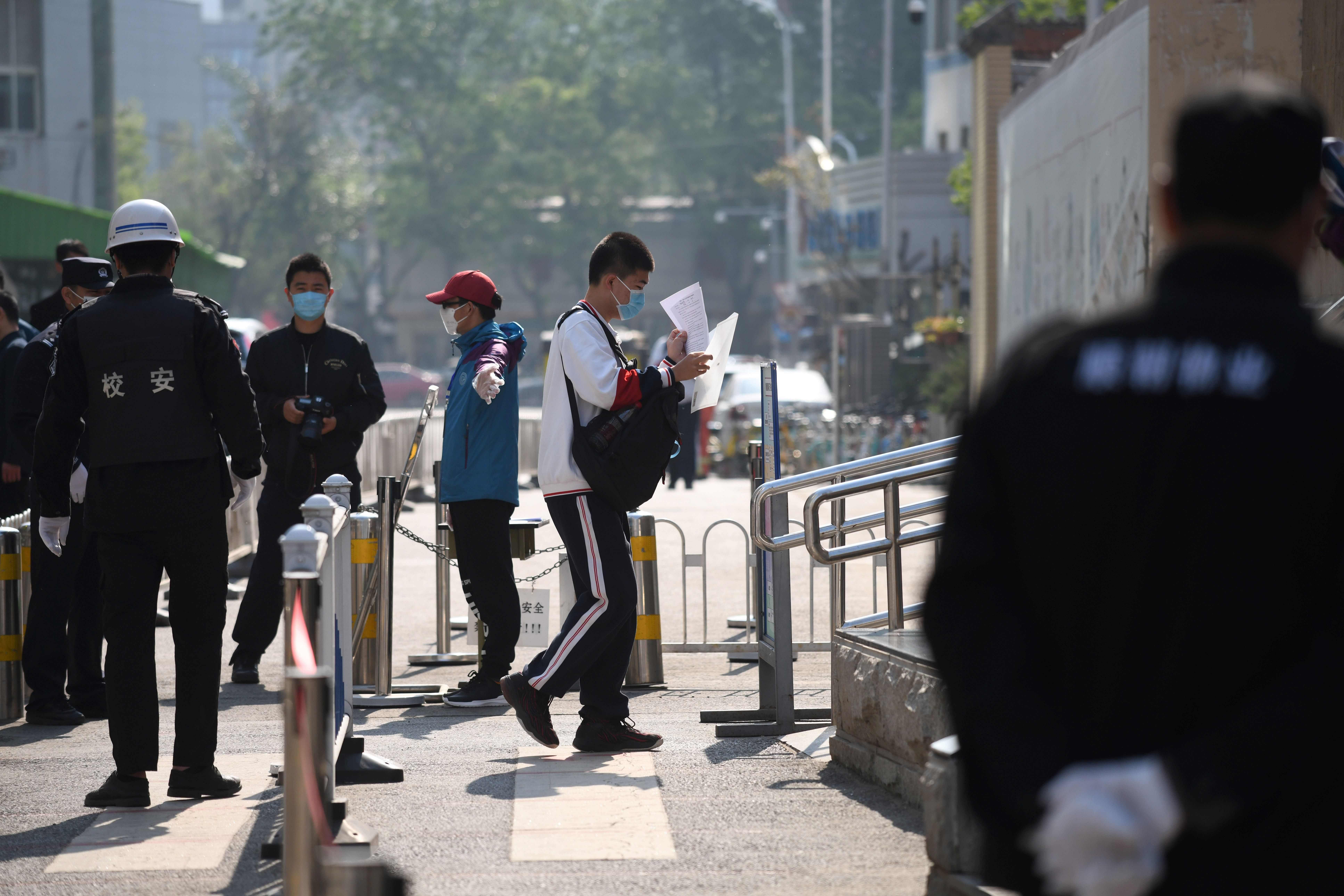 A student walks past police and officials as he arrives at a high school in Beijing. (AFP Photo)