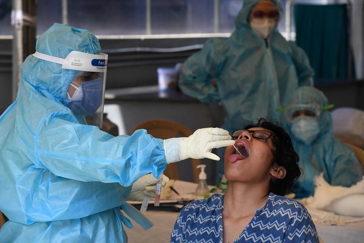 A Health official takes a swab sample from the throat of a girl at a COVID-19 coronavirus testing centre during a government-imposed nationwide lockdown as a preventive measure against the COVID-19 coronavirus, in New Delhi on April 27, 2020. Credit: AFP Photo