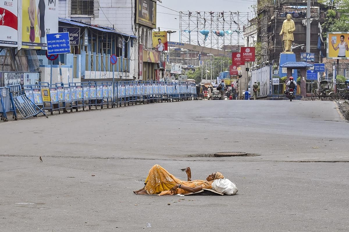 A homeless woman rests in the middle of a deserted road outside the Howrah station in Kolkata on Sunday. PTI