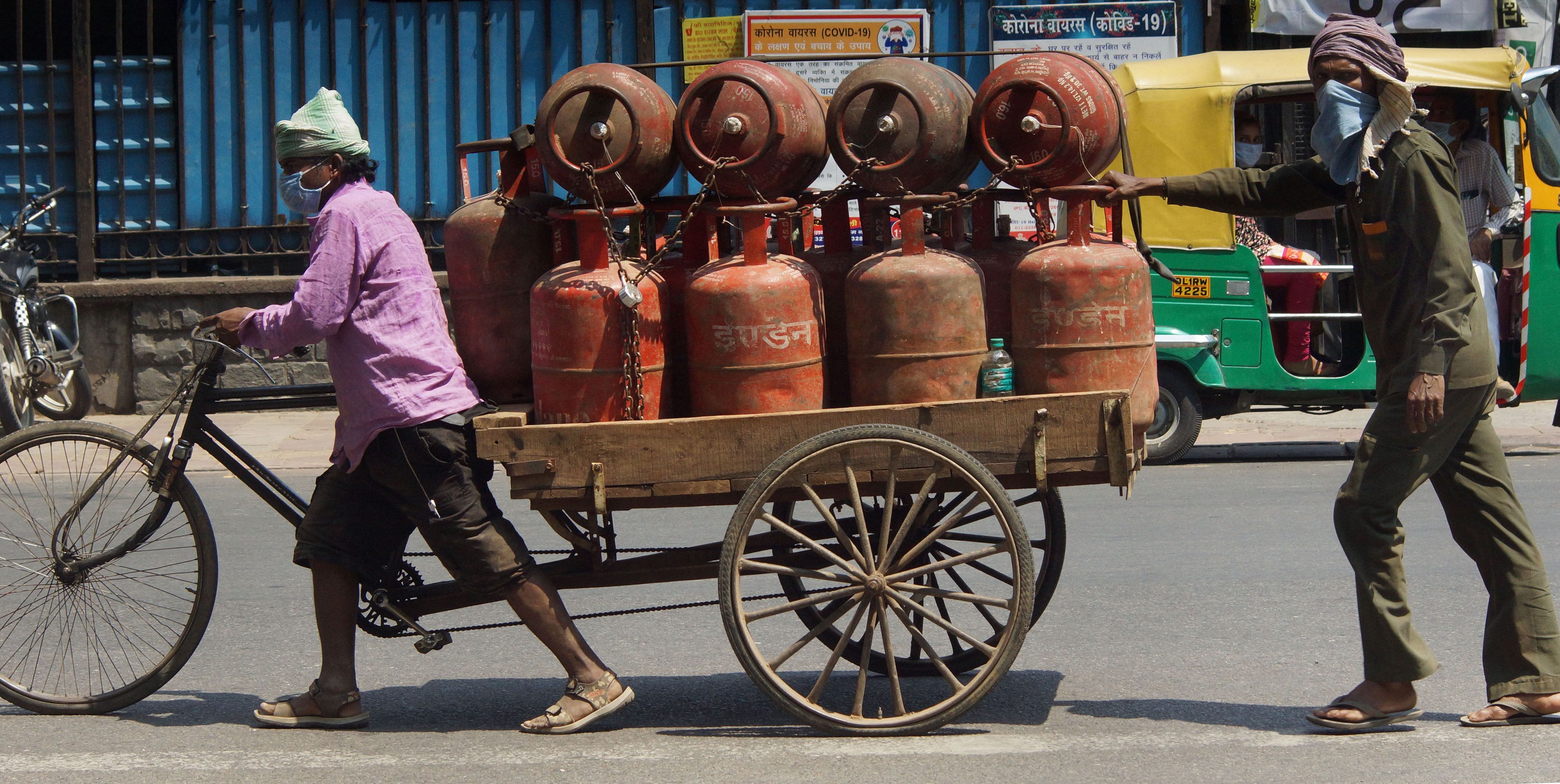 Workers push a cart loaded with LPG cylinders, during the nationwide lockdown to curb the spread of coronavirus. (PTI Photo)
