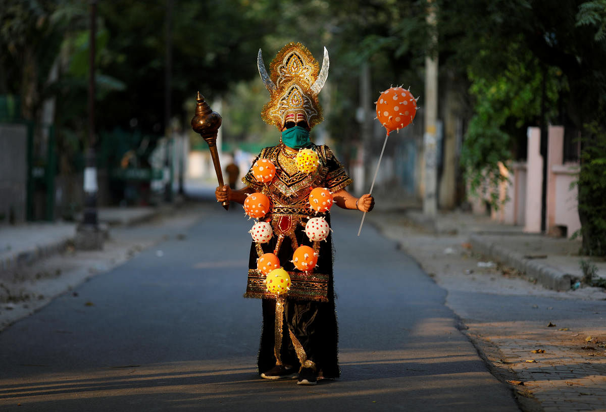 A local resident dressed as Yamraj or Hindu god of death, wearing a novel coronavirus-themed balloon necklace, gestures as he poses during an awareness about social distancing and staying at home organised by Delhi police during a nationwide lockdown to slow the spreading of the coronavirus disease (COVID-19), in New Delhi, India, April 28, 2020.  Credit: Reuters Photo