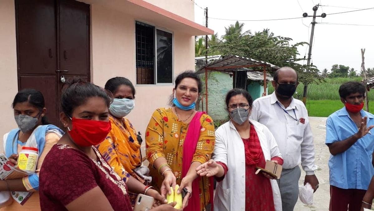 Vice president of Human Rights Committee Neena Patel and others distribute food supplements and nutritious food to residents of B T Lalitha Naik Layout in Mandya on Tuesday.