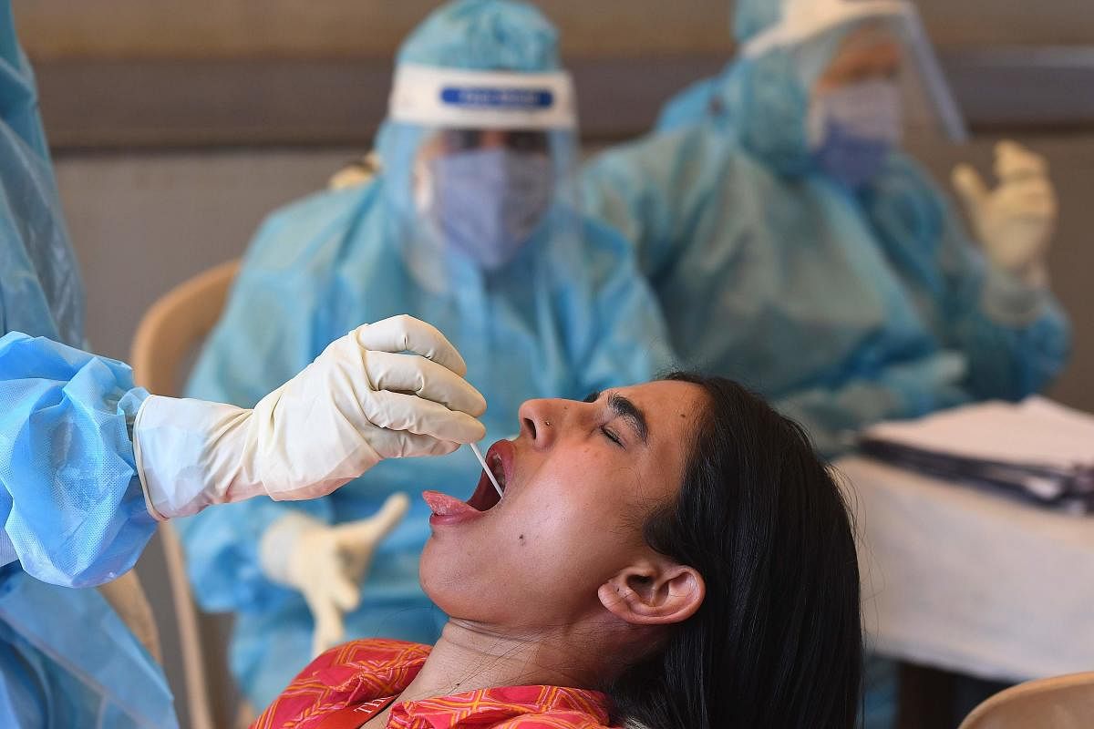 A Health official takes a swab sample from the throat of a girl at a COVID-19 coronavirus testing centre (AFP Photo)