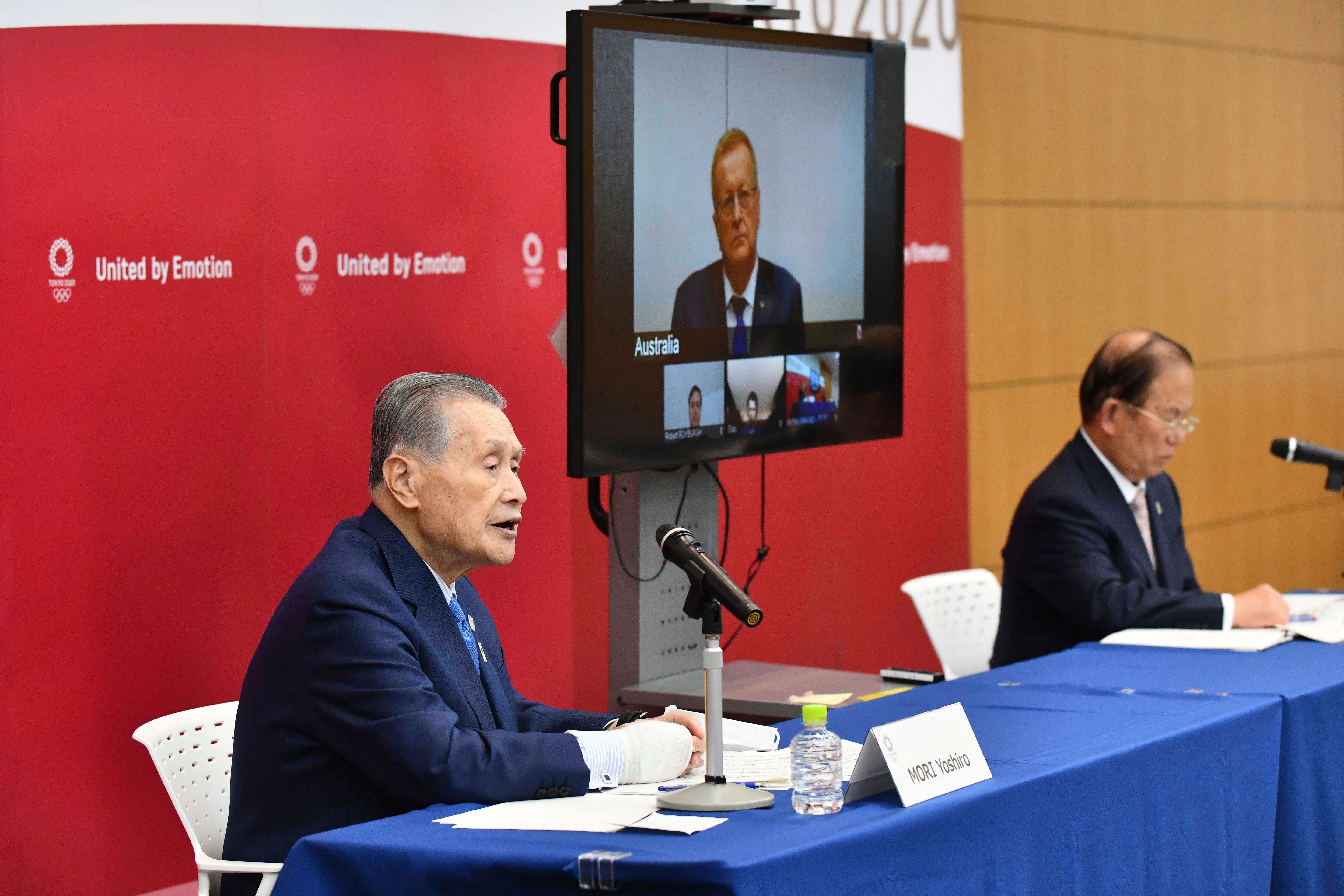  Tokyo 2020 Organizing Committee President Yoshiro Mori, left, and CEO Toshiro Muto, right, attend teleconference with International Olympic Committee member John Coates. (AP Photo)
