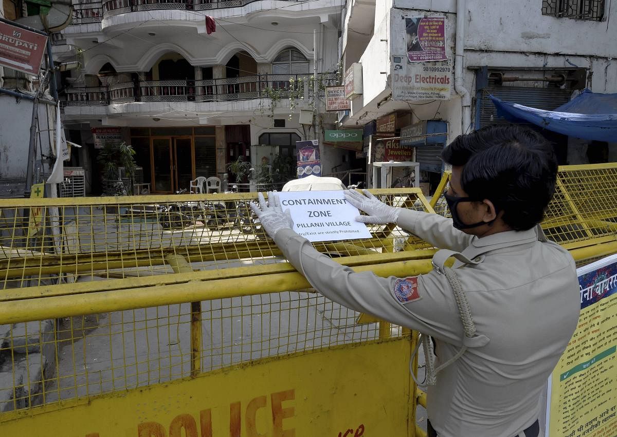 :A security guard pastes a notice on a barricade at Pilanji village area, identified as a COVID-19 containment zone, during the nationwide lockdown to curb the spread of coronavirus, in New Delhi, Tuesday, April 28, 2020. (PTI Photo)