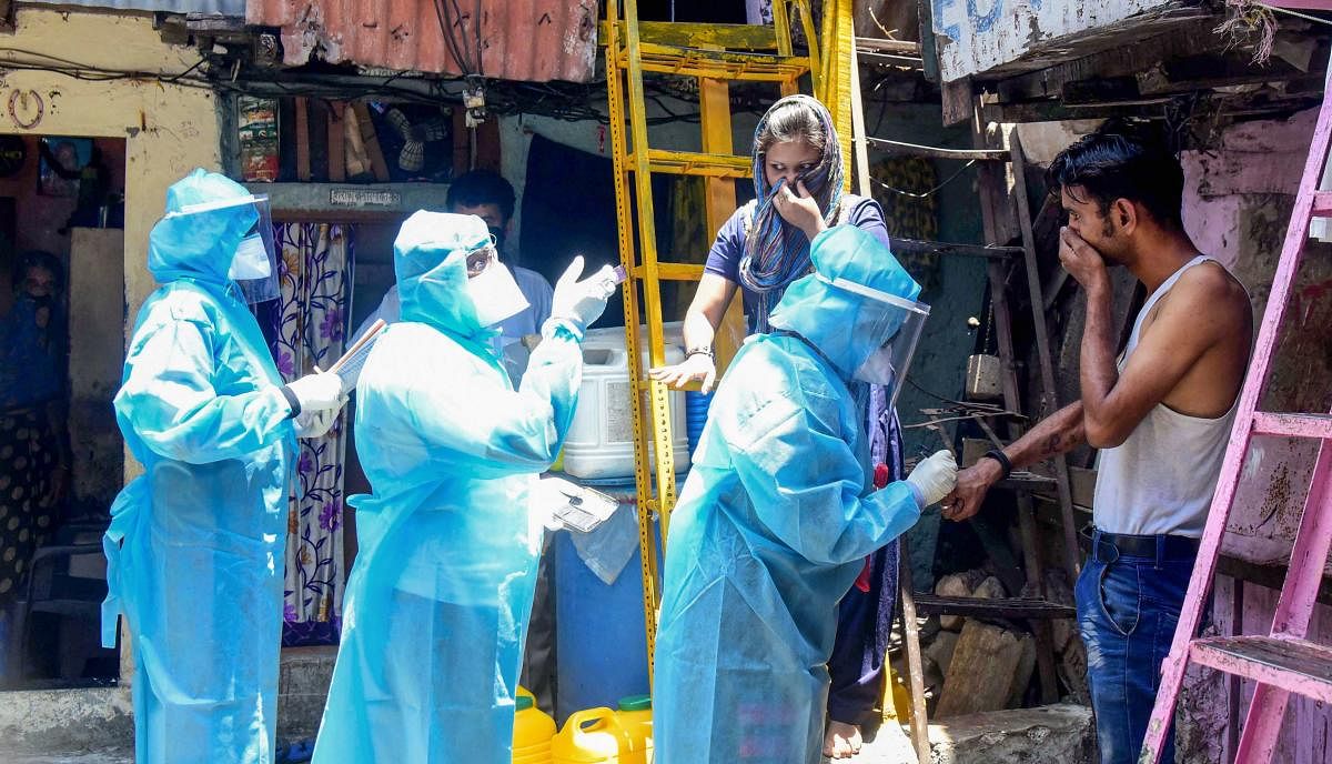 Health workers wearing protective suits screen resident of Kumbharwada during a house-to-house health survey, after detection of some COVID-19 positive cases, during the nationwide lockdown, at Dharavi in Mumbai, Wednesday, April 29, 2020. (PTI Photo)