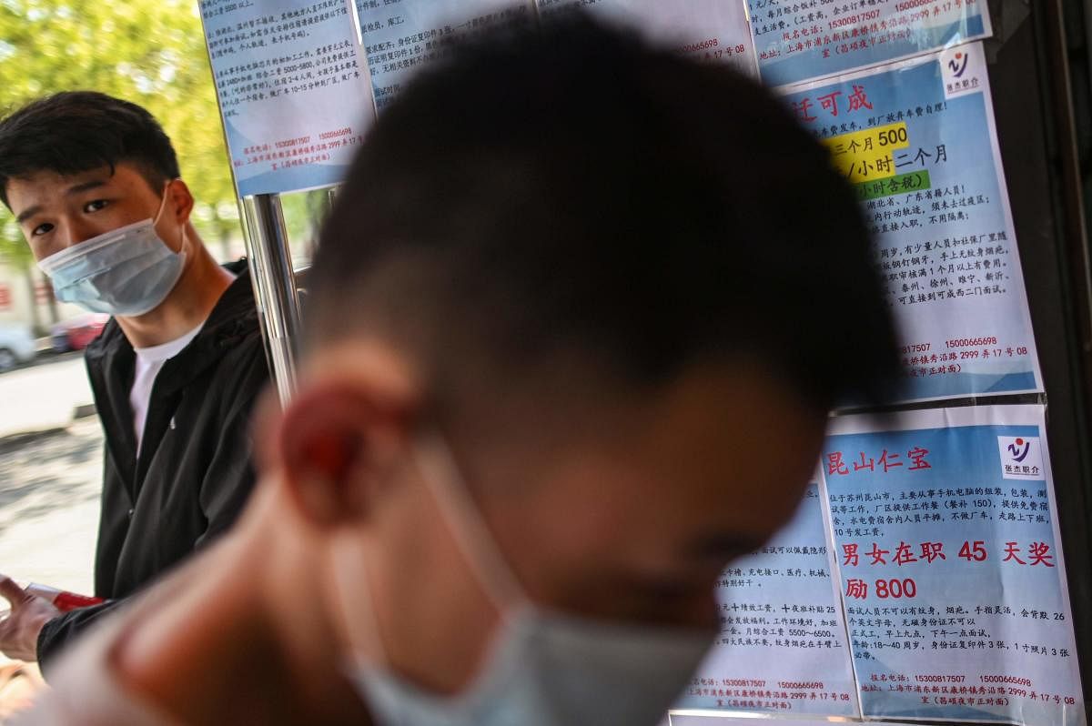 Men wearing face masks are seen next to papers with new job offers in an employment agency in Shanghai. AFP