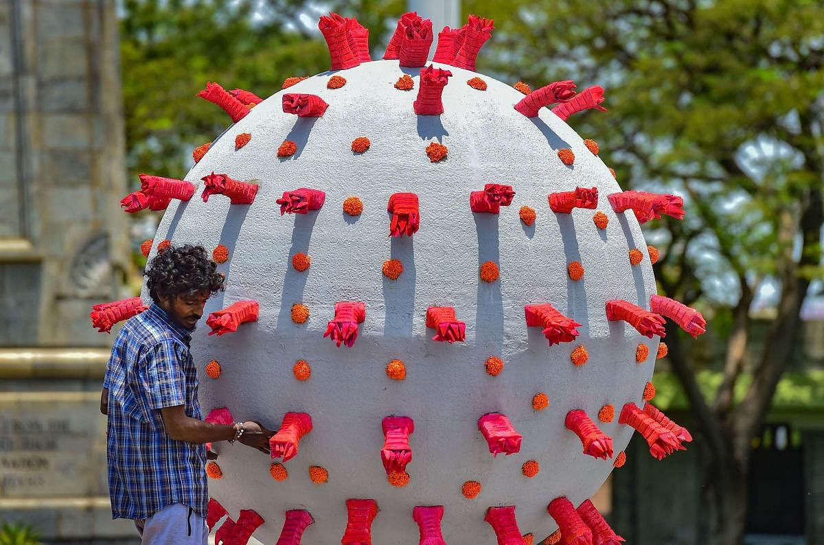 An artist gives a final touch to a model based on coronavirus placed alongside a road to raise awareness, in Chennai, Wednesday, April 29, 2020. PTI