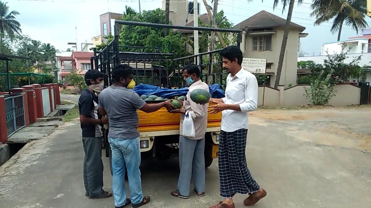 People purchase watermelons from a photographer-turned-vegetable and fruit vendor in Kushalnagar.