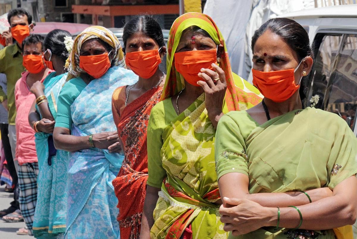 Women wearing masks stand in a queue to collect ration kits distributed during the nationwide lockdown imposed in wake of the coronavirus pandemic, in Bengaluru, Thursday, April 30, 2020. (PTI Photo)
