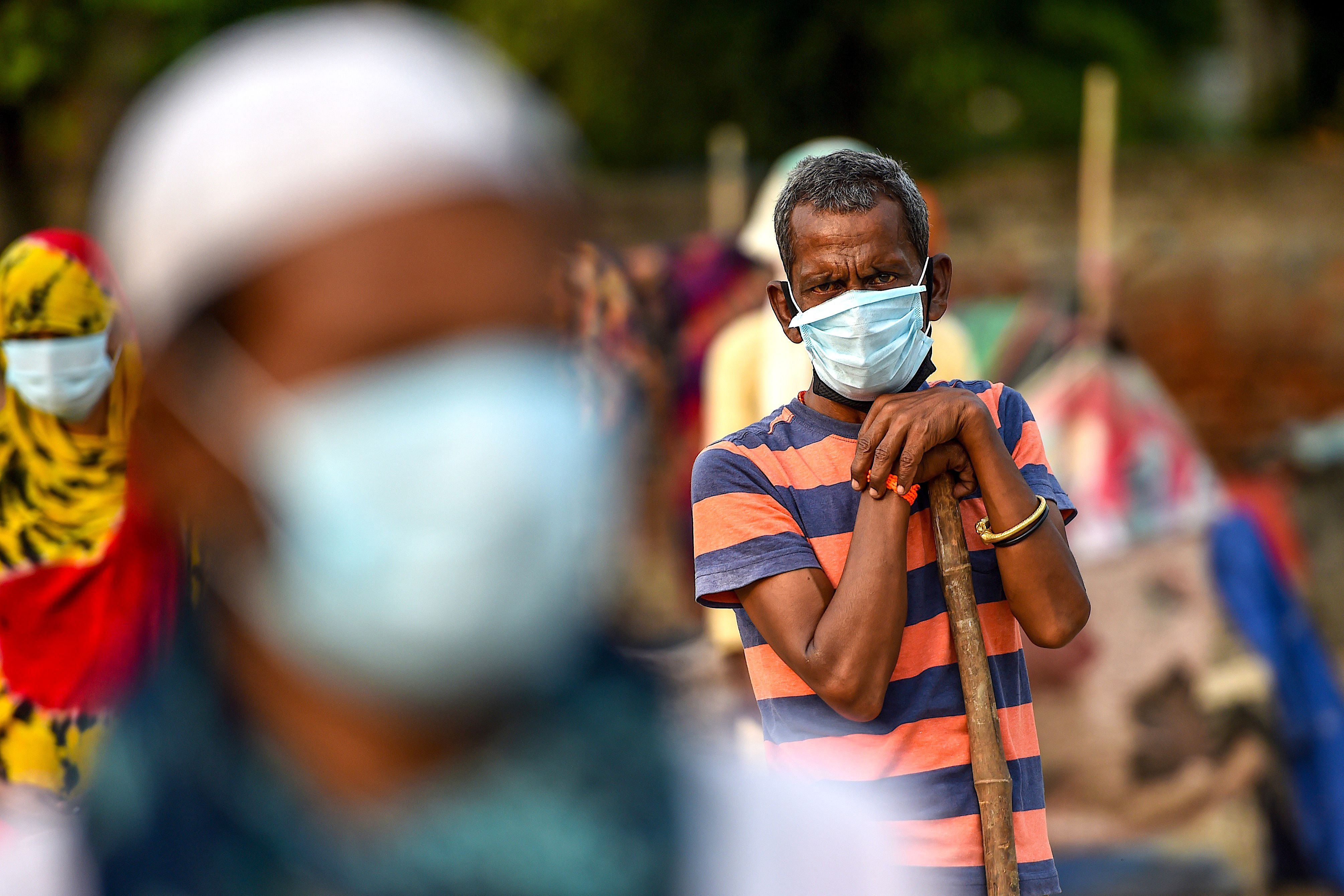 A man waits with others for groceries to be distributed by police personnel during a government-imposed nationwide lockdown as a preventive measure against the COVID-19 coronavirus, in Faridabad. (AFP Photo)