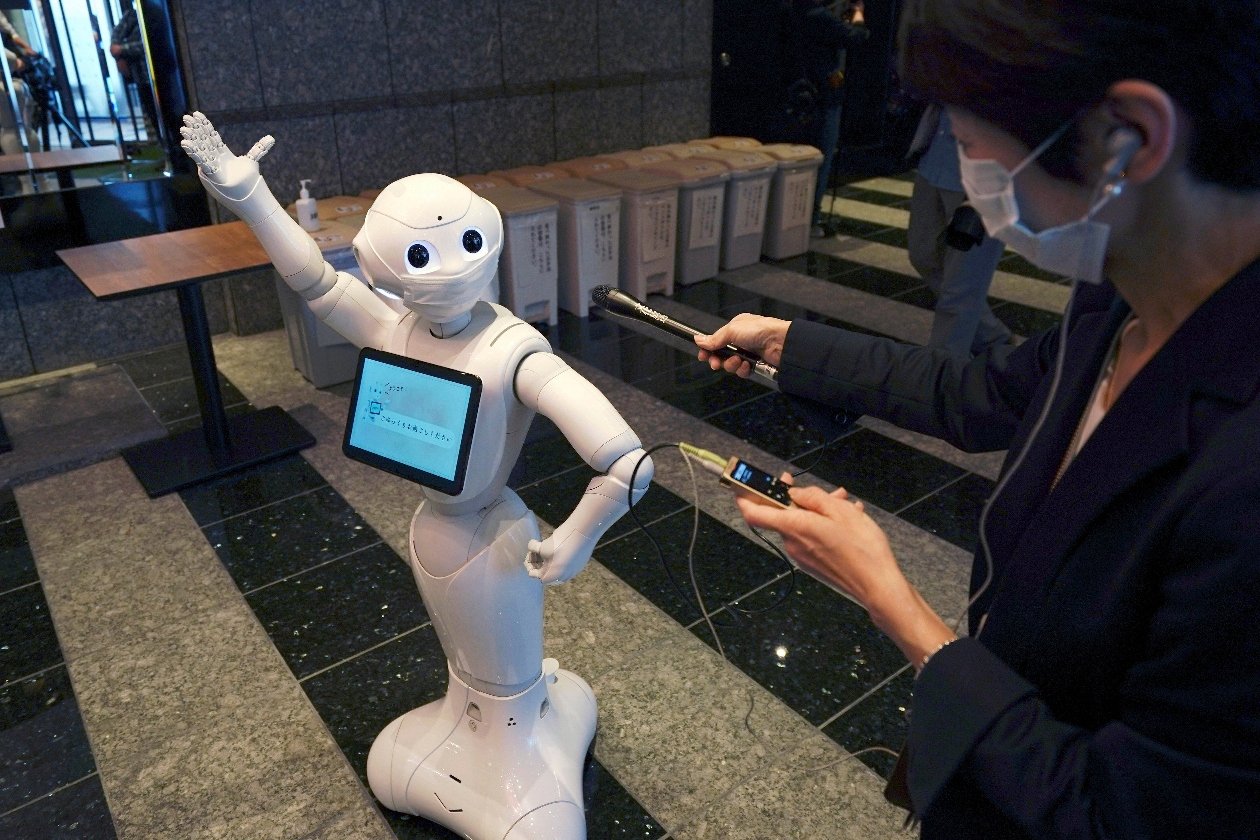 A humanoid robot Pepper wearing a face mask greets a radio reporter at the lobby of a hotel for the new coronavirus COVID-19 patients with mild symptoms. (AP photo)