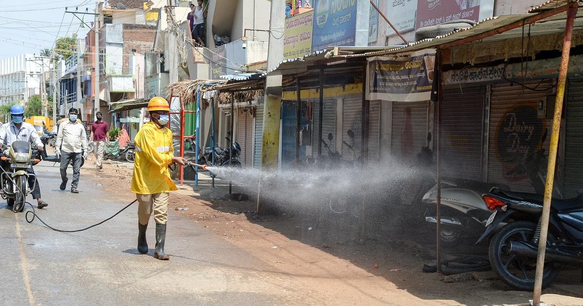A fire and emergency personnel sprays disinfectant in Jalinagar in Davangere on Thursday after a person tested positive for Covid-19. DH Photo/Satish Badiger