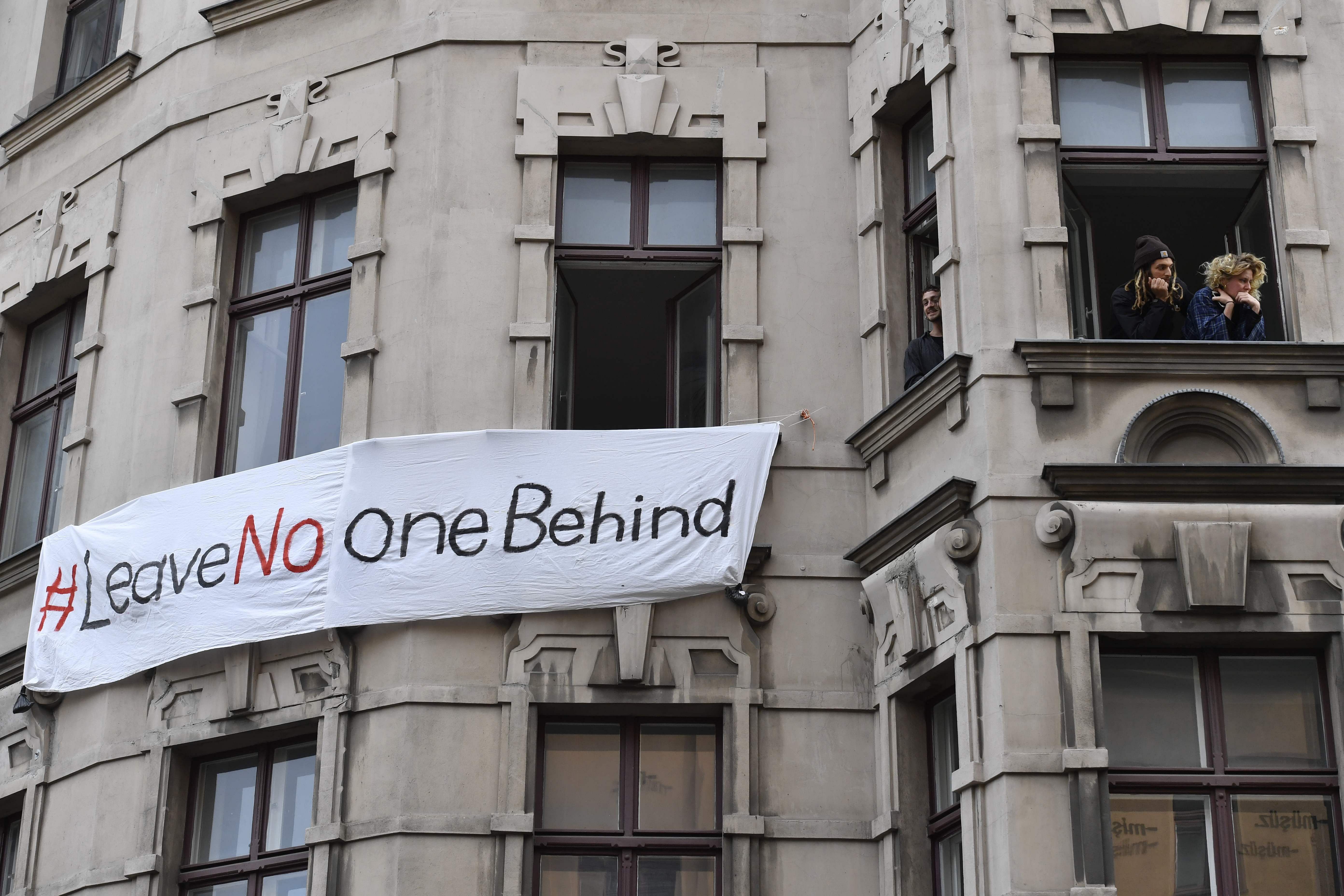 People look out the window of a house with a banner which reads "#leave no one behind" in Berlin's Kreuzberg district on May 1, 2020, during May Day protests amid the COVID-19 outbreak caused by the novel coronavirus. (AFP photo)