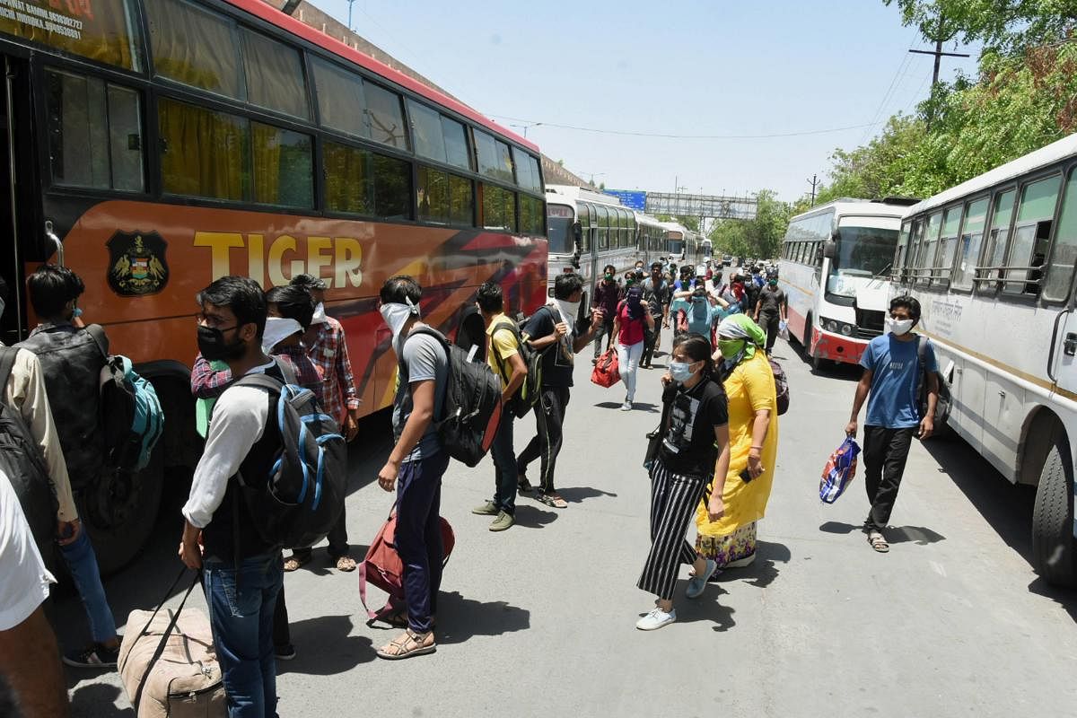 Migrants from various states board a bus to reach their native places at a bus stand (PTI Photo)