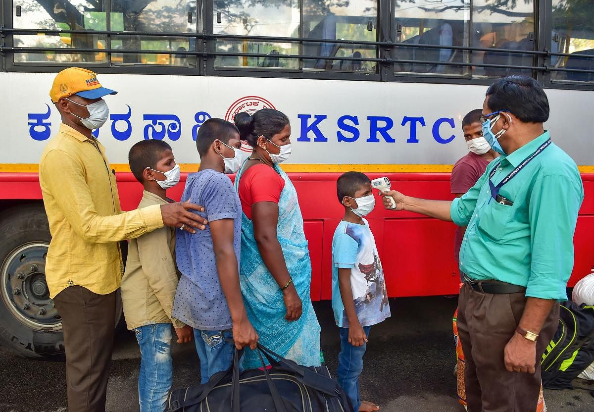 A medic conducts thermal scanning of the migrant people before they board a special bus for their respective native places, amid ongoing COVID-19 lockdown in Bengaluru, Friday, May 1, 2020. (PTI Photo_
