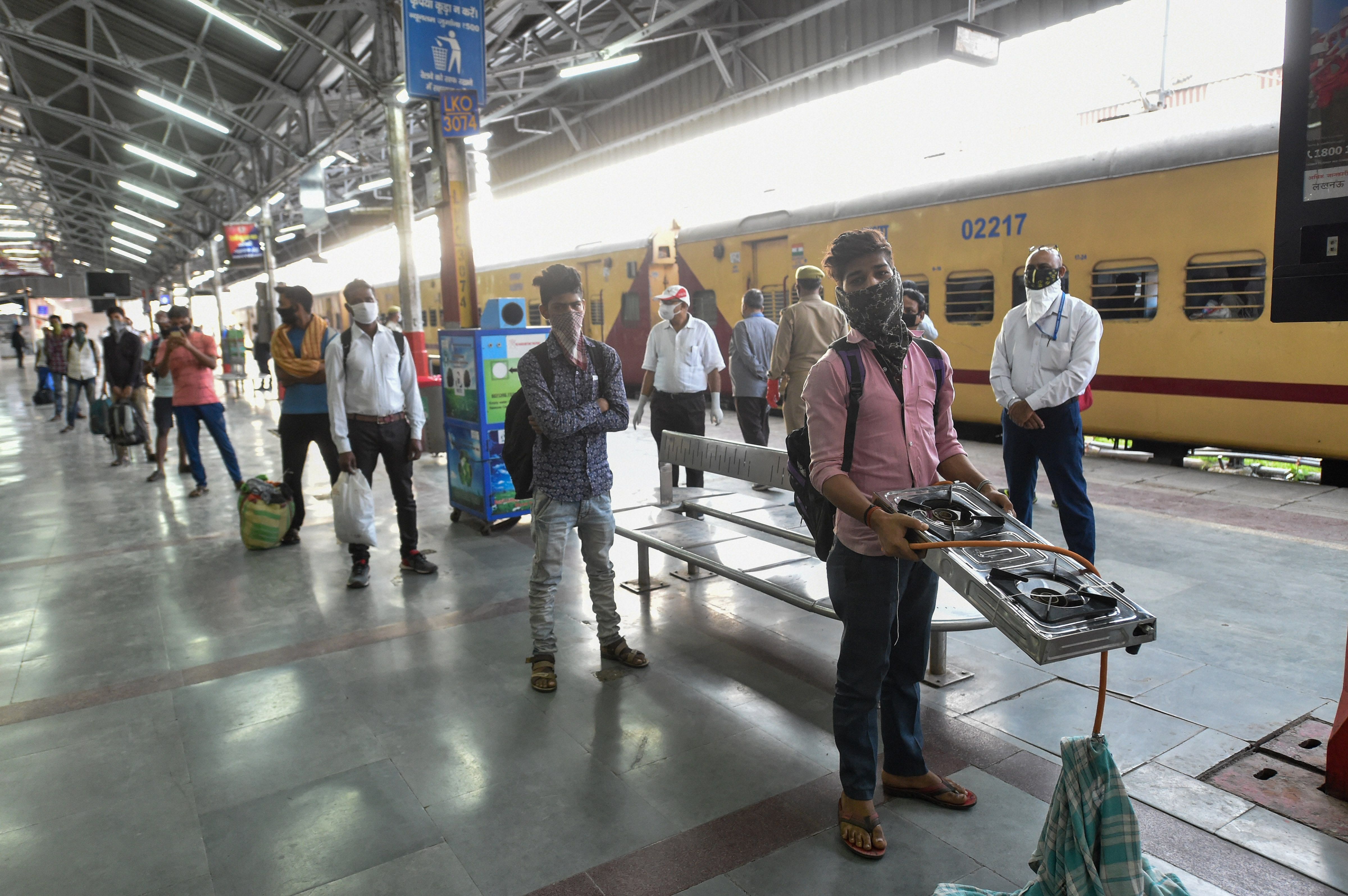Migrants who have arrived from Nashik by a special train stand in a queue maintaining social distancing at Charbagh railway station, during the ongoing COVID-19 lockdown, in Lucknow. (PTI Photo)