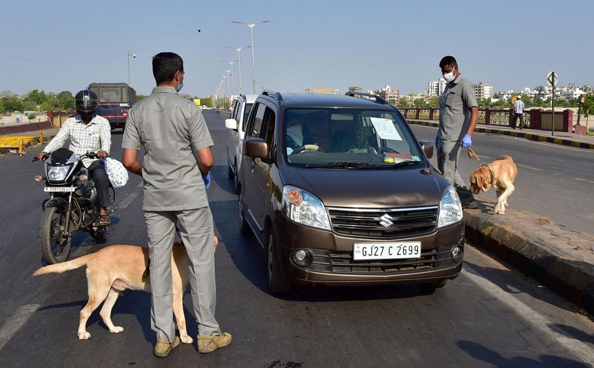 Police personnel with sniffer dogs check the vehicles of commuters in Ahmedabad. PTI