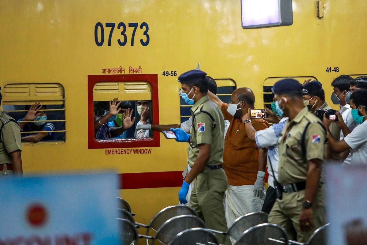 In this photo taken on May 1, 2020, migrant workers greet Kerala state officials out of the windows as they sit on a train leaving to Odisha at Aluva railway station in Kochi.  Credit: AFP Photo