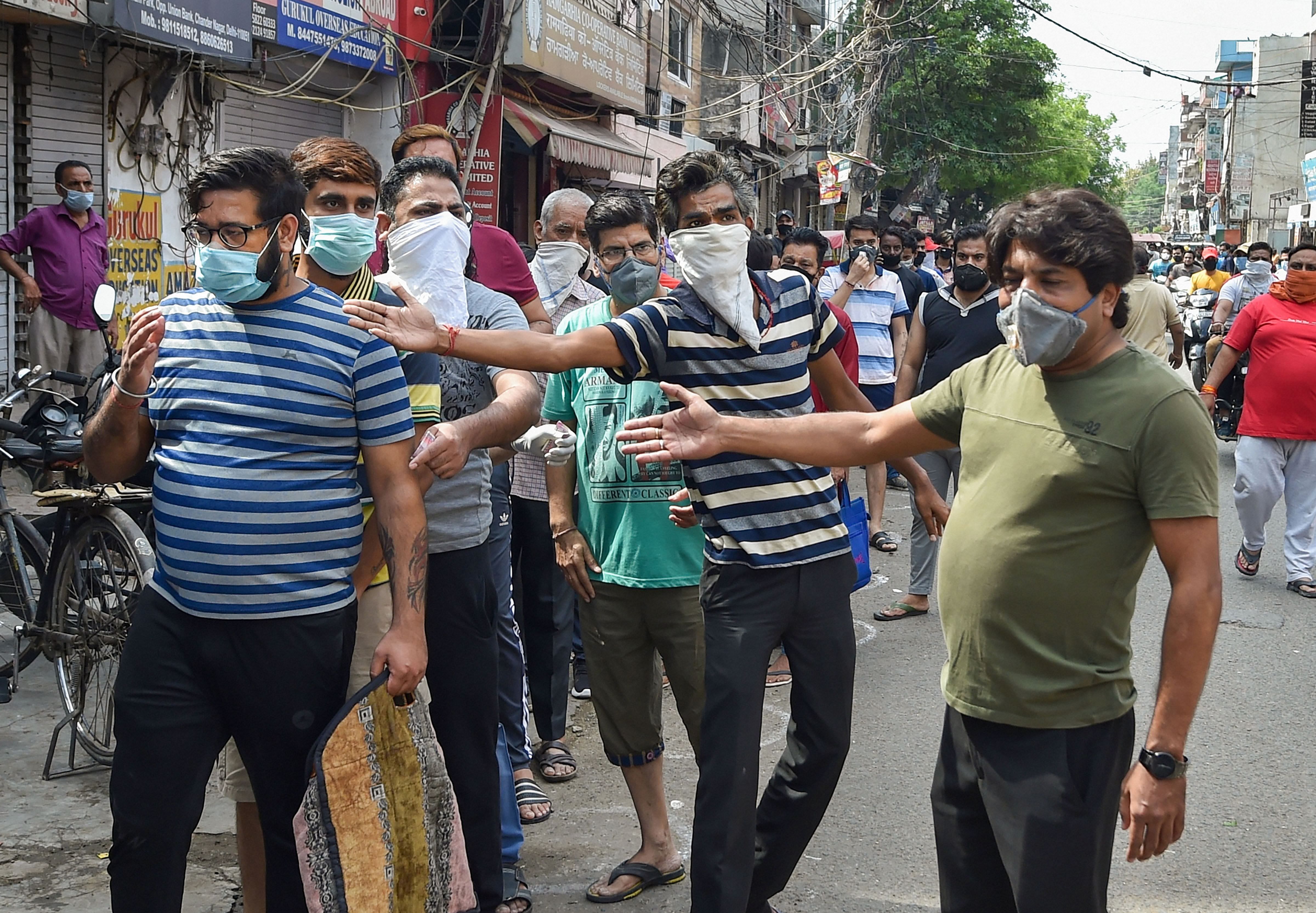 Some people engage in a scuffle while others stand in a queue outside a wine shop after authorities allowed the sale of liquor with certain restrictions, during ongoing COVID-19 nationwide lockdown at Chander Nagar in East Delhi. (Credit: PTI Photo)