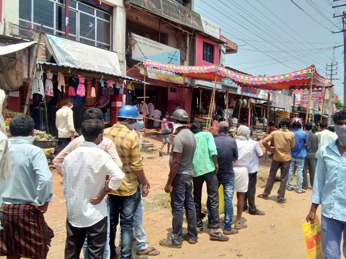 People wait in a queue outside a liquor outlet in Tarikere.