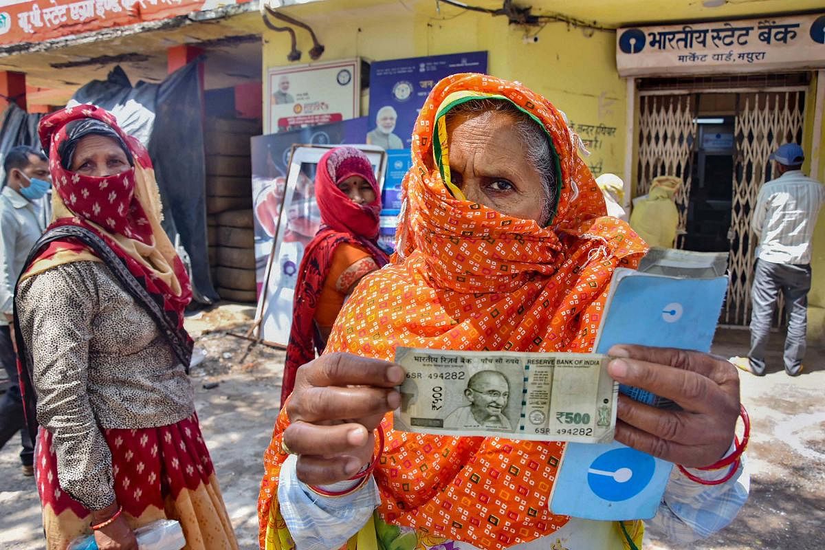 An elderly woman shows a 500 rupee note after withdrawing from her Jan Dhan account, as the government releases the second installment of the COVID-19 lockdown relief fund, in Mathura, Monday, May 4, 2020. (PTI Photo) 