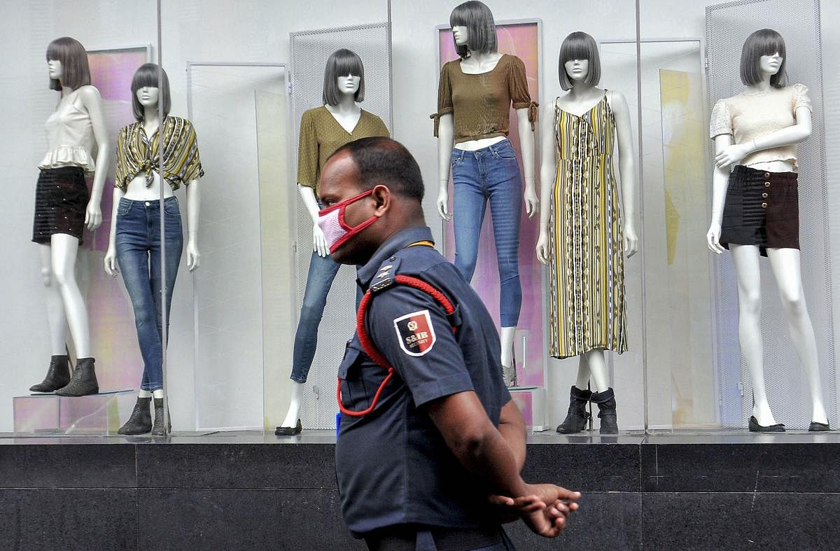 A security guard wearing a face mask walks past mannequins of a closed shopping mall, during a nationwide lockdown in the wake of coronavirus pandemic. PTI