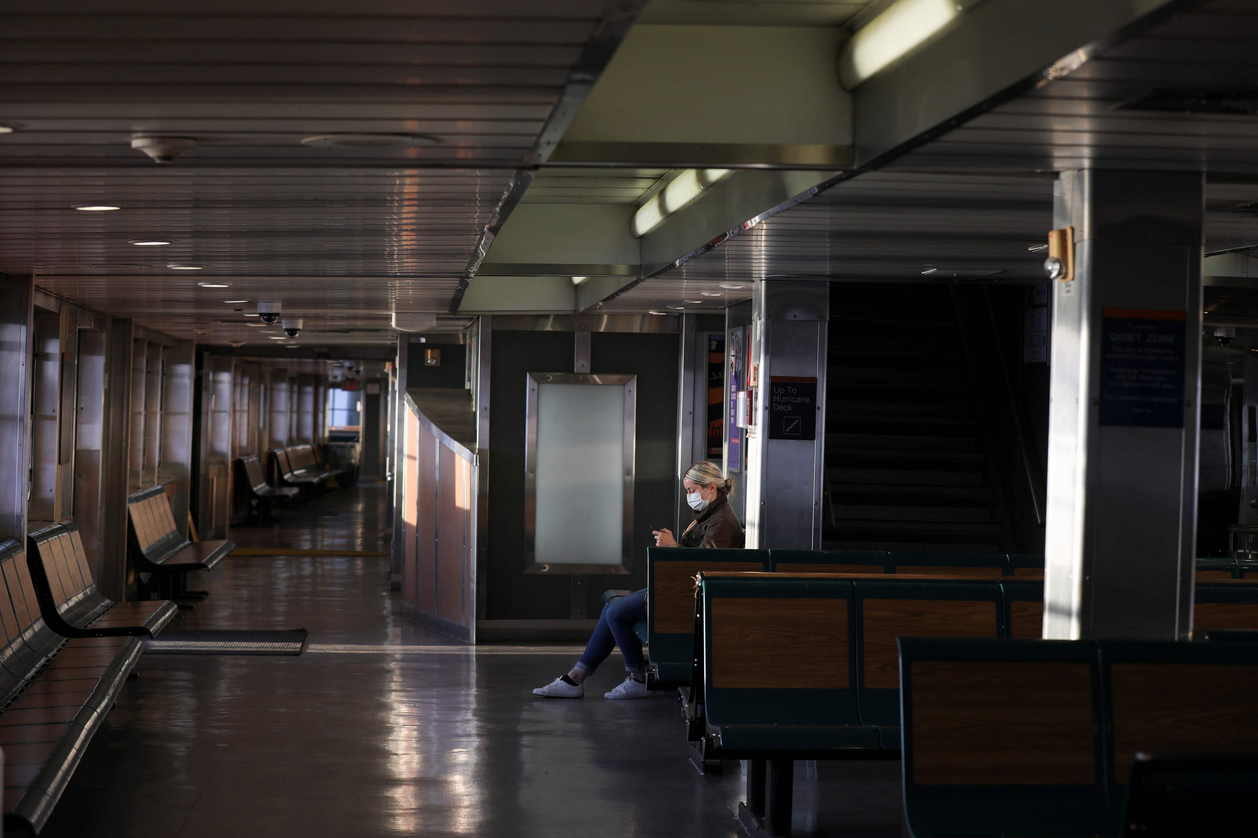 A commuter on the Staten Island Ferry wears a protective face mask and sits alone during the outbreak of the coronavirus disease (COVID-19) in Manhattan. (Credit: Reuters)