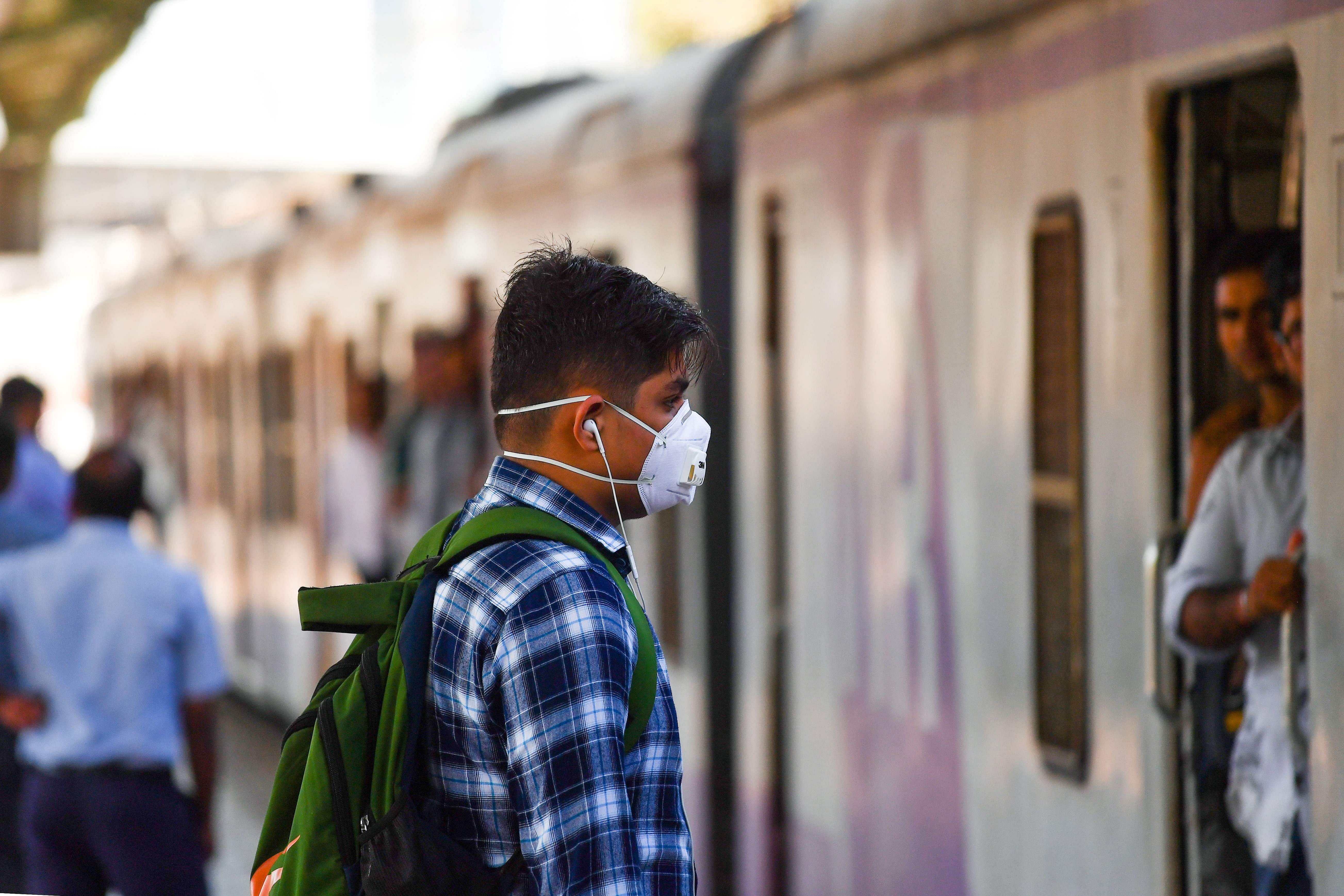 A man wearing a facemask amid concerns over the spread of the COVID-19 coronavirus arrives at a train station in Mumbai. (Credit: AFP)